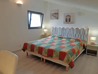 a bedroom with a bed with a colorful quilt on it at Douceur du soir - Duplex 45m2 - Terrasse - Jardinet - Wifi fibre - Plage à pied in Porticcio
