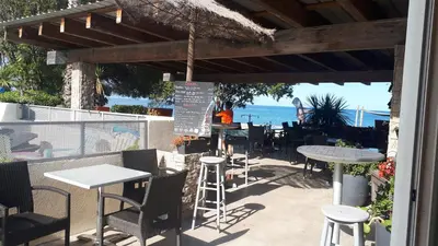 a patio with tables and chairs and the ocean at Résidence Les Marines de Moriani pieds dans l'eau duplex avec terrasses vue mer, 4-8 pers in San-Nicolao