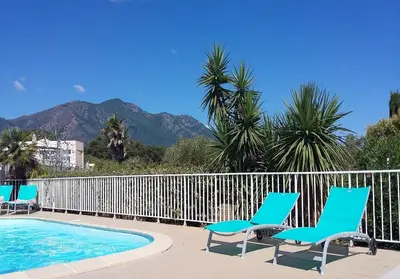 two chairs and a swimming pool with mountains in the background at Kazamasavani - Belle maison proche mer in Cervione