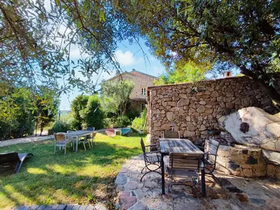 a table and chairs in a yard next to a stone wall at Entre mer & maquis, l'âme de la Corse en gîtes de charme avec jacuzzi, proche Ajaccio in Peri