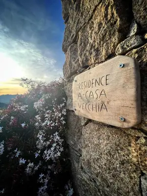 a sign on the side of a stone wall at Entre mer & maquis, l'âme de la Corse en gîtes de charme avec jacuzzi, proche Ajaccio in Peri