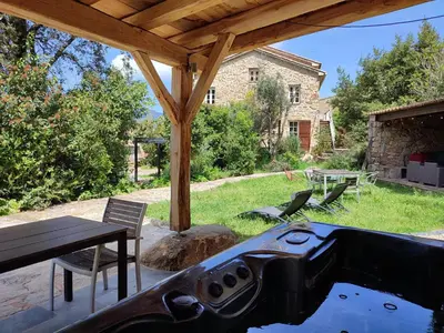 a outdoor kitchen with a grill and a picnic table at Entre mer & maquis, l'âme de la Corse en gîtes de charme avec jacuzzi, proche Ajaccio in Peri