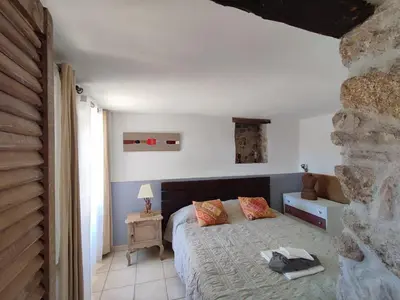 a bedroom with a bed and a stone wall at Entre mer & maquis, l'âme de la Corse en gîtes de charme avec jacuzzi, proche Ajaccio in Peri