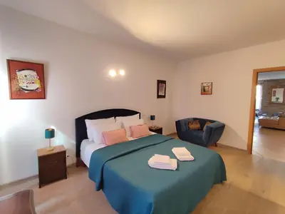 a bedroom with a bed with a blue blanket and a chair at T3 de 140m2 pour 7 pers- Extra centre Ajaccio - À 5 min à pied des plages - Classé 5 étoiles - CASA DI ARTISTI in Ajaccio