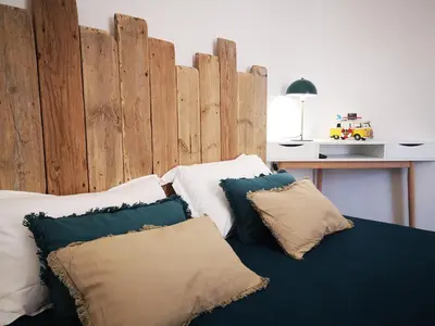 a bedroom with a wooden headboard and pillows on a bed at T3 de 140m2 pour 7 pers- Extra centre Ajaccio - À 5 min à pied des plages - Classé 5 étoiles - CASA DI ARTISTI in Ajaccio