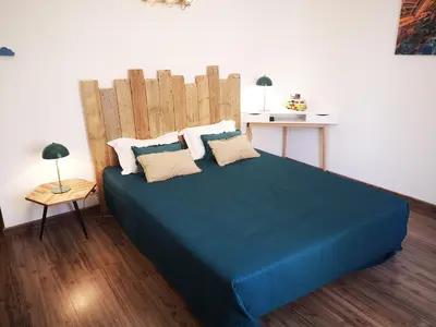 a bedroom with a blue bed with a wooden headboard at T3 de 140m2 pour 7 pers- Extra centre Ajaccio - À 5 min à pied des plages - Classé 5 étoiles - CASA DI ARTISTI in Ajaccio