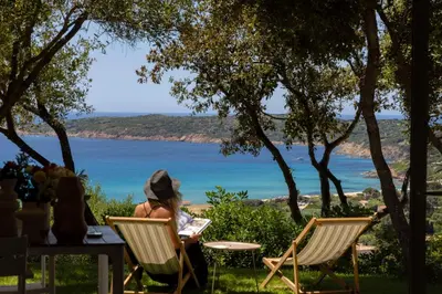 a woman sitting in a chair looking at the ocean at Résidence Omigna in Cargèse