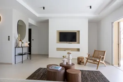 a living room with white walls and a tv on a wall at Résidence Omigna in Cargèse