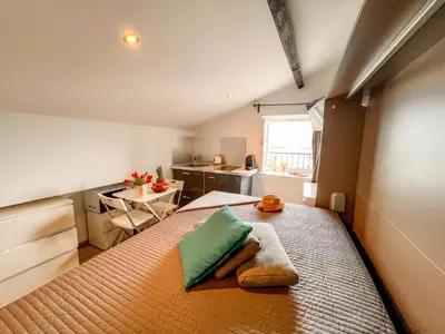 a bedroom with a bed with a green pillow on it at Les Studios du Pêcheur - Hypercentre - Clim - City Trip in Ajaccio
