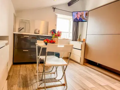 a kitchen with a table and chairs and a refrigerator at Les Studios du Pêcheur - Hypercentre - Clim - City Trip in Ajaccio