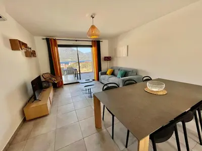 a living room with a table and a couch at APPART-NEUF-VUE MER- 6 PERS in Propriano