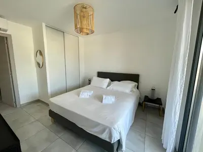 a bedroom with a bed with white sheets and pillows at APPART-NEUF-VUE MER- 6 PERS in Propriano