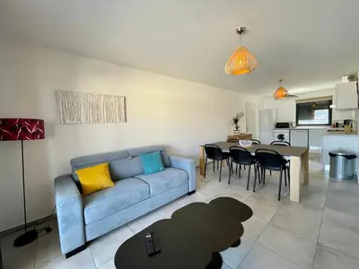 a living room with a blue couch and a table at APPART-NEUF-VUE MER- 6 PERS in Propriano