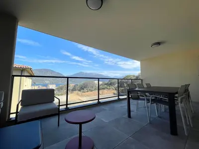 a balcony with a table and chairs and a view at APPART-NEUF-VUE MER- 6 PERS in Propriano