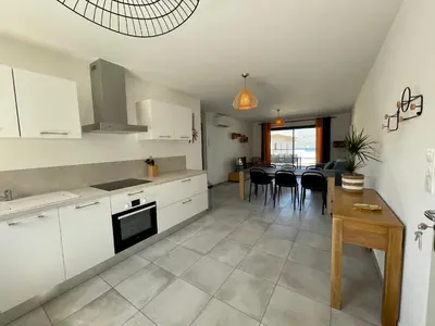 a kitchen and dining room with white cabinets and a table at APPART-NEUF-VUE MER- 6 PERS in Propriano