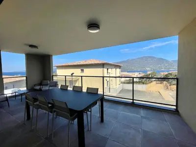 a dining room with a table and chairs and a large window at APPART-NEUF-VUE MER- 6 PERS in Propriano