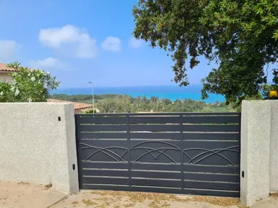 a black gate in front of a house at Superbe Villa, incroyable vue mer, avec piscine privative à Solenzara in Togna