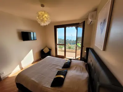 a bedroom with a large bed with a large window at Superbe Villa, incroyable vue mer, avec piscine privative à Solenzara in Togna