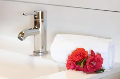 a flower on a bathroom counter next to a towel at Mare E Monti Chalets in Porto Pollo