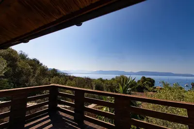 a wooden balcony with a view of the water at Mare E Monti Chalets in Porto Pollo