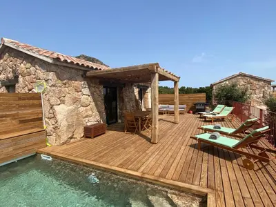 a wooden deck with chairs and a swimming pool at Bergeries de charme Caselle di Conca in Conca