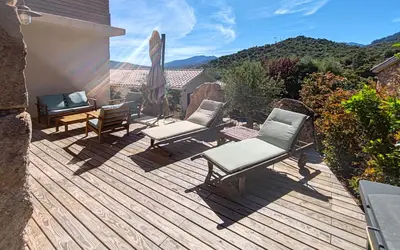 a wooden deck with chairs and an umbrella and a table at Bergeries de charme Caselle di Conca in Conca