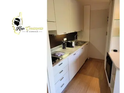 a small kitchen with white cabinets and a sink at Studio 4 pers Piscine Chauffée accès à pied à la plage Santa Giulia in Porto-Vecchio