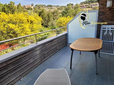 a table and chair on a balcony with a view at Studio 4 pers Piscine Chauffée accès à pied à la plage Santa Giulia in Porto-Vecchio