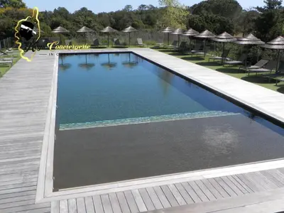 a large swimming pool with chairs and umbrellas at Studio 4 pers Piscine Chauffée accès à pied à la plage Santa Giulia in Porto-Vecchio