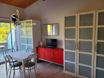 a dining room with a table and a red cabinet at Studio 4 pers Piscine Chauffée accès à pied à la plage Santa Giulia in Porto-Vecchio