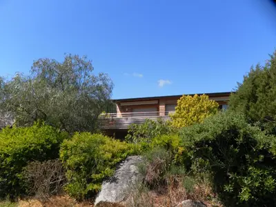 a house on a hill with bushes and trees at Studio 4 pers Piscine Chauffée accès à pied à la plage Santa Giulia in Porto-Vecchio
