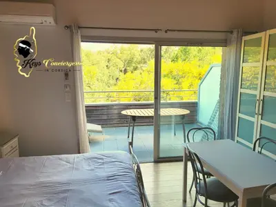 a room with a balcony with a bed and a table at Studio 4 pers Piscine Chauffée accès à pied à la plage Santa Giulia in Porto-Vecchio