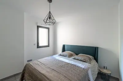 a bedroom with a bed with a green headboard and a window at L'eclat de Stagnola in Pietrosella