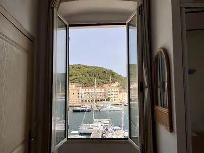 a window with a view of a harbor with boats at Appartements Bonifacio AcquaViva in Bonifacio