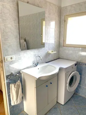 a bathroom with a sink and a washing machine at Appartements Bonifacio AcquaViva in Bonifacio