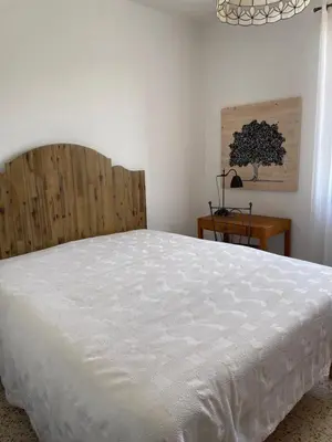 a bedroom with a white bed and a wooden headboard at Villa près de la Plage in Grosseto-Prugna