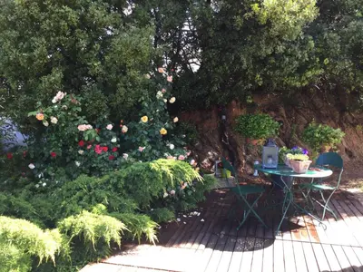 a table and chairs in a garden with flowers at Villa près de la Plage in Grosseto-Prugna