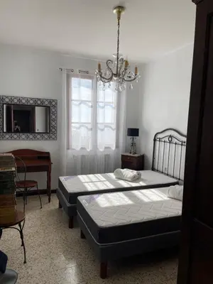 a bedroom with two beds and a table and a chandelier at Villa près de la Plage in Grosseto-Prugna