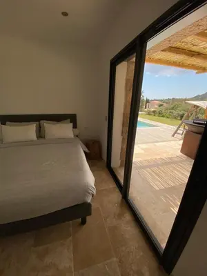 a bedroom with a bed and a sliding glass door at Villa de charme avec piscine à Ajaccio in Alata