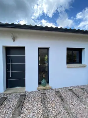 a white house with a black garage door at Villa de charme avec piscine à Ajaccio in Alata