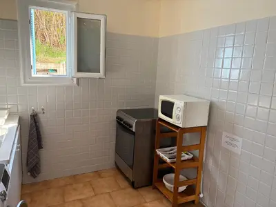a kitchen with a microwave on a counter with a sink at Joli T2 dans villa in Corte