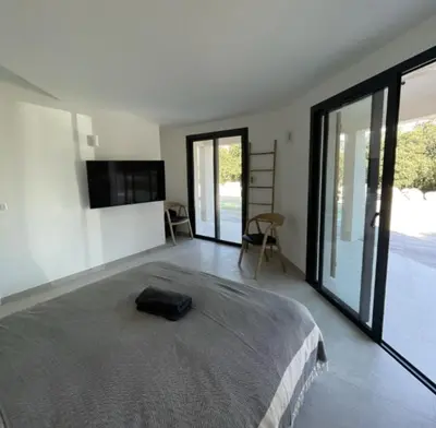 a bedroom with a large bed and sliding glass doors at Villa Pura Vida Di Olmuccio in Sainte-Lucie de Porto-Vecchio