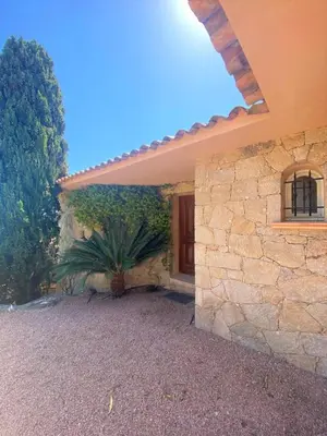 a stone house with a palm tree in front of a building at Villa Clementina Di Punta d'Arasu in Sainte-Lucie de Porto-Vecchio