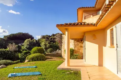 a house with a yard with blue mats on the grass at Villa Clementina Di Punta d'Arasu in Sainte-Lucie de Porto-Vecchio