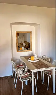 a dining room with a table and chairs and a mirror at Appartement Vue mer en plein centre de Cargese in Cargèse