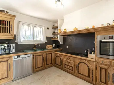 a kitchen with wooden cabinets and stainless steel appliances at Holiday Home Villa Vaccaja by Interhome in Porto-Vecchio