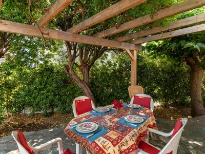 a table and chairs under a wooden pergola at Holiday Home Villa Irène by Interhome in Linguizzetta