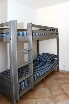 two bunk beds in a room with blue and gray pillows at Holiday Home T3 Cabine by Interhome in Borgo