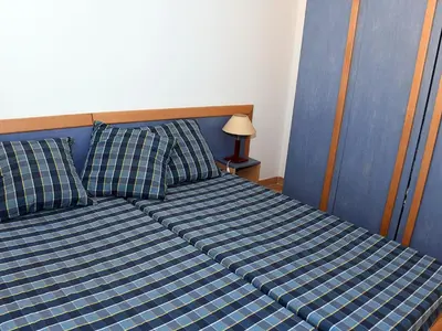 a bed with a blue and white checkered sheets and pillows at Holiday Home T3 Cabine by Interhome in Borgo