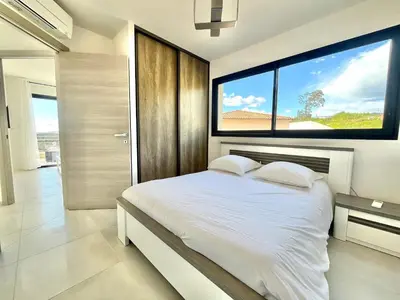 a white bedroom with a bed and a large window at T3 Acum - Domaine prestigieux sur Agosta plage - Exceptionnel 3 étoiles in Porticcio